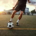 Male football player hits the ball on the field